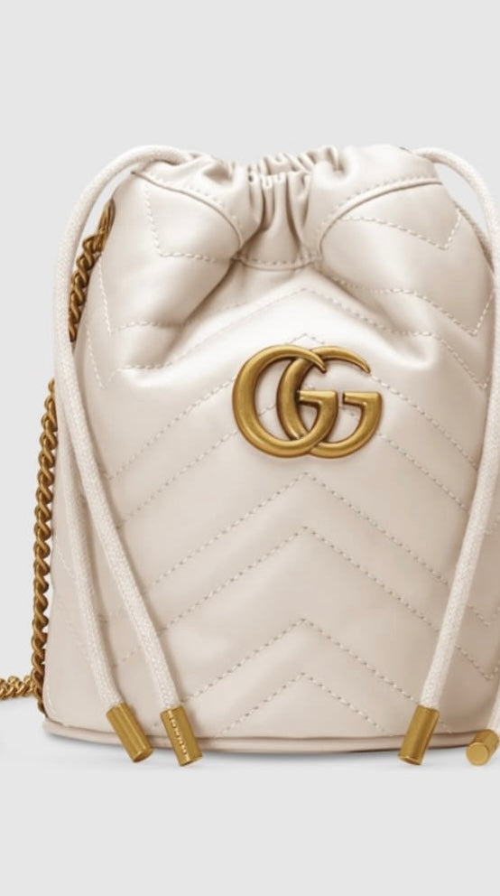 White quilted handbag with gold chain and logo on a light gray background
